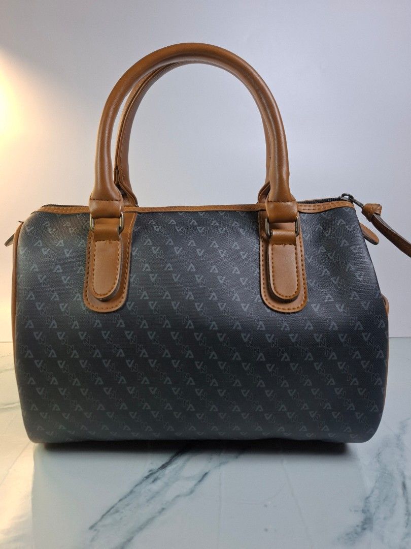 Kriabe Monogram Handbag Brown Grey (Category: Purses & Pouches) located in Pasay City. Submitted by onick_79 (Listing ID 1469931092, Image 2). Description: -Dimensions: L 29 x H 19 x W 14 cm - Brand: Kriabe - Color/Pattern: Dark grey with all-over monogram - Material/Trim: Brown faux leather trim - Handles: Dual top handles - Details: Gold lettering logo patch on the front - Closure: Zip top closure - Condition: Clean inside and out, sturdy struc