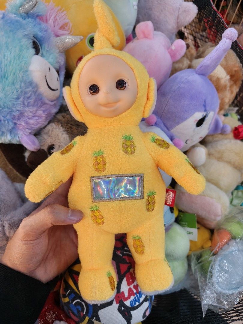 Laa-Laa Teletubbies pineapple pattern plush toy (Category: Plushies & Soft Toys) located in La Trinidad. Submitted by charlsensei (Listing ID 1469893873, Image 1). Description: - Character: Yellow Laa-Laa from Teletubbies - Design: All-over pineapple pattern with a shiny silver screen on the tummy - Features: Classic plastic face, curly antenna, and small red label near the right arm - Material: Soft textured fabric - Condition: Clean, well-maint