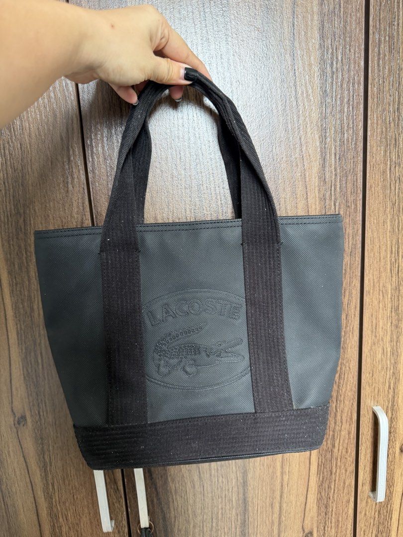 Lacoste Black Canvas Tote Bag with Embossed Logo (Category: Tote Bags) located in Quezon City. Submitted by mdjheavyequipment (Listing ID 1469788145, Image 1). Description: - Brand: Lacoste - Color: Black canvas with light cream fabric interior lining - Design: Large embossed crocodile logo on the front - Features: Double webbed fabric handles, reinforced base, and secure zip top closure - Pockets: One interior zipper pocket and open slip pockets