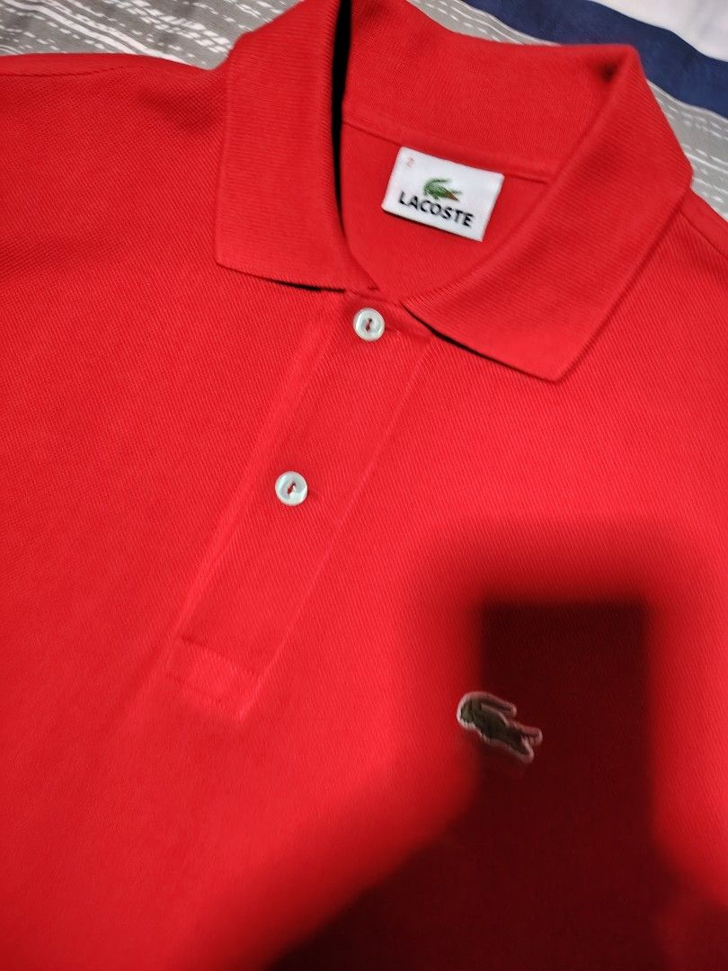 Lacoste Red Polo Shirt Size 2 (Category: Tshirts & Polo Shirts ) located in Manila. Submitted by snooks1938 (Listing ID 1469933445, Image 2). Description: - Brand: Lacoste - Color: Bright red - Size: Men's Size 2 - Material: Quality cotton pique fabric with clean stitching - Details: Classic collar with two white buttons and iconic embroidered green crocodile logo - Condition: Good as new..sealed in clear plastic packaging...