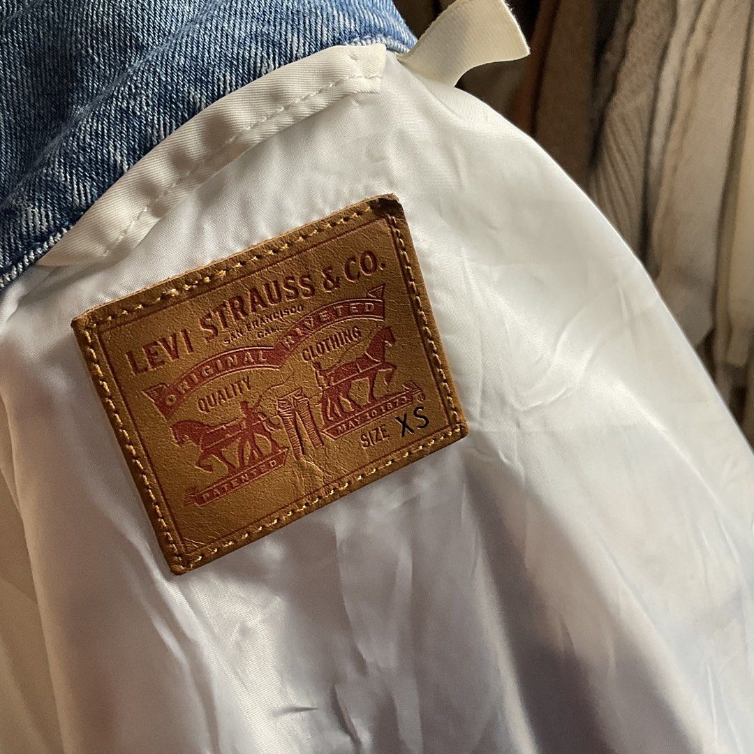 Levi's Denim and White Bomber Jacket Size XS (Category: Coats, Jackets and Outerwear) located in La Trinidad. Submitted by di_tiyak (Listing ID 1469778365, Image 2). Description: - Brand: Levi's - Style: Hybrid denim and white nylon bomber jacket - Size: XS - Features: Utility zip pocket on the left arm, silver-tone engraved metal buttons, signature red tab on chest pocket - Closure: Button-up front with a classic collar - Lining: 100% polyester 