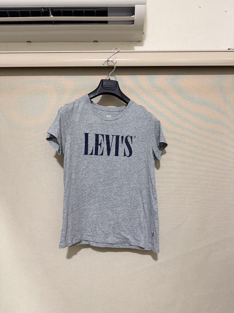 Levi's Grey Logo T-Shirt Size M (Category: Shirts) located in Cavite. Submitted by mgd.blessed (Listing ID 1469905826, Image 1). Description: - Brand: Levi's - Color: Grey with dark blue lettering - Size: Medium (Regular Fit) - Material: Soft cotton blend - Style: Classic crew neck - Condition: Clean overall, ready to wear, with a small hole near the right shoulder seam as pictured.