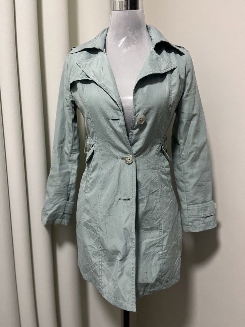Light green trench coat with buttons and collar (Category: Coats, Jackets and Outerwear) located in Angeles City. Submitted by pinkpool (Listing ID 1469764668, Image 1). Description: - Color: Light green - Style: Mid-length trench coat with large lapel collar - Closure: Front button closure with fitted waist - Details: Side pockets and stylish strap accents on cuffs - Best for: Transitional weather outerwear.