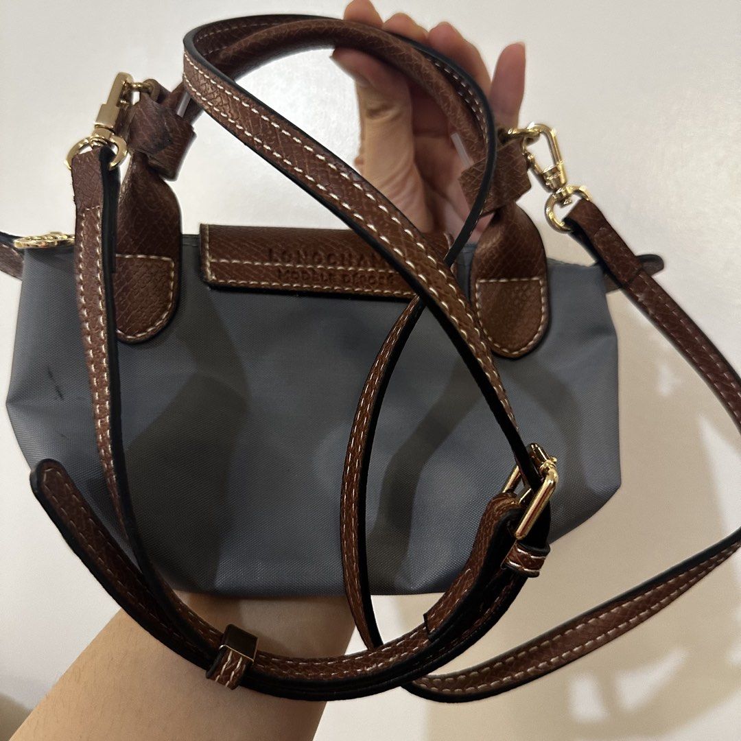 Longchamp Le Pliage Cuir Extra Small Top Handle Bag (Category: Luxury Bags & Wallets) located in Makati City. Submitted by cosmicfire.4ba272 (Listing ID 1469840179, Image 2). Description: - Color & Material: Grey nylon body with stylish brown leather flap and handle trim - Hardware: Elegant gold-tone snap button closure and details - Closure: Secure zippered top to keep your items safe - Versatility: Includes a detachable crossbody strap for hand