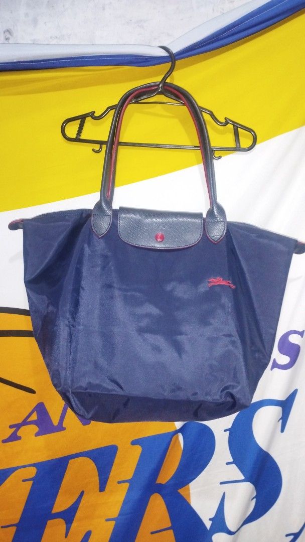 Longchamp Le Pliage Nylon Tote Bag Navy Blue (Category: Luxury Bags & Wallets) located in Manila. Submitted by beckster_online_luxuryshop (Listing ID 1469901161, Image 1). Description: - Brand: Longchamp - Color: Navy blue with contrasting red edging and red embroidered jockey logo - Material: Lightweight, durable nylon - Closure: Flap closure with snap button and embossed horse logo - Condition: Clean with minimal signs of wear - Features: Folds