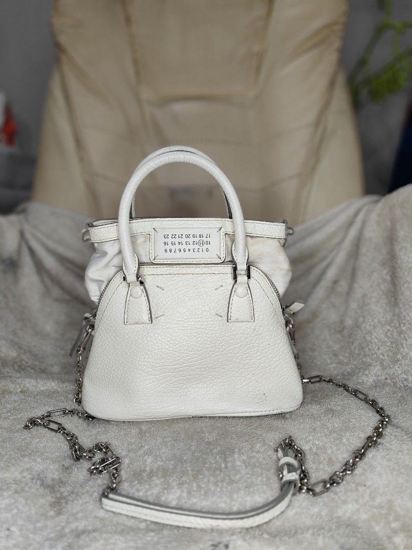 Maison Margiela 5AC Micro White Leather Bag (Category: Luxury Bags & Wallets) located in Cebu City. Submitted by cherreymie70208 (Listing ID 1469786172, Image 1). Description: - Maison Margiela 5AC Micro Bag -Repainted color on leather lips part inside - Color: Textured White Leather - Features iconic numeric logo patch and metal feet on bottom - Dual top handles and detachable chain strap included - Secure zip closure with interior tag (Style co