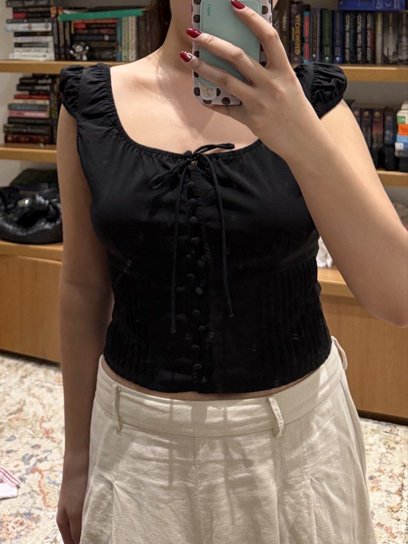 MANGO Black corset style crop top with tie string front (Category: Sleeveless) located in Meycauayan. Submitted by m4teri4lgirl (Listing ID 1469773681, Image 2). Description: - Color: Black - Style: Corset crop top with vertical ribbing - Details: Tie string across the chest, front button closure, and short cap sleeves - Condition: Worn once, very clean and well-maintained - Styling Tip: Perfectly pairs with high-waisted pants or skirts.