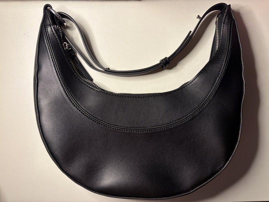 Mango Black Crescent Shoulder Bag (Category: Shoulder Bags) located in Imus. Submitted by jpgworks (Listing ID 1469925408, Image 1). Description: - Brand: Mango - Style: Black crescent shoulder bag - Material: Smooth faux leather - Hardware: Silver tone with zipper closure - Strap: Adjustable with metal buckle - Interior: Lined with an inner zip pocket and brand label tag .