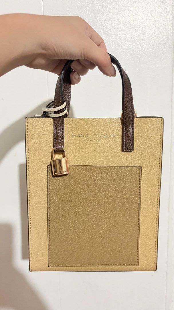 Marc Jacobs Leather Tote Bag (Category: Tote Bags) located in Baguio. Submitted by meiji50 (Listing ID 1469930120, Image 1). Description: Marc Jacobs tote bag in a multi-tone beige, brown, and cream colorway. Textured pebbled leather material with structured upright handles. Front slip pocket accented with a gold-tone padlock and key charm. Clean dark interior lining. Includes original brand tag tucked in the front pocket..