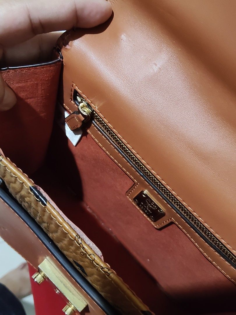 MCM Brown Leather Top Handle Shoulder Bag (Category: Luxury Bags & Wallets) located in Cebu City. Submitted by almzcorner (Listing ID 1469922805, Image 3). Description: - Brand: MCM - Material: Brown pebbled leather with signature monogram pattern - Details: Solid brown front pocket & gold-tone hardware with engraved branding - Interior: Red fabric lining with a zippered pocket and brand plaque - Inclusion: Matching adjustable shoulder strap incl