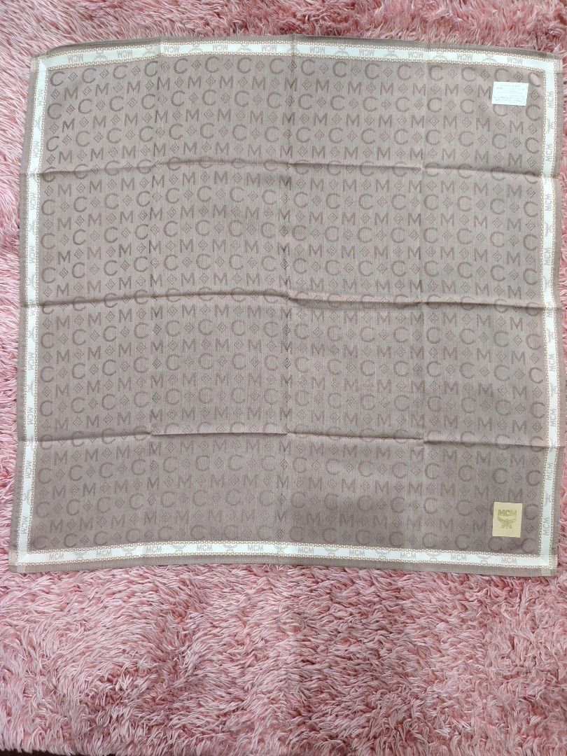 MCM Hanky NEW (Category: Scarves) located in Valenzuela. Submitted by anna.banana10 (Listing ID 1469788305, Image 1). Description: - Brand: MCM - Material: Lightweight silk - Design: All-over monogram pattern with MCM and C motifs, finished with a cream and brown patterned border - Details: Features a gold-tone fabric brand label and original tag attached - Shape: Square - Condition: Brand new with original tag; has minor folded crease lines from