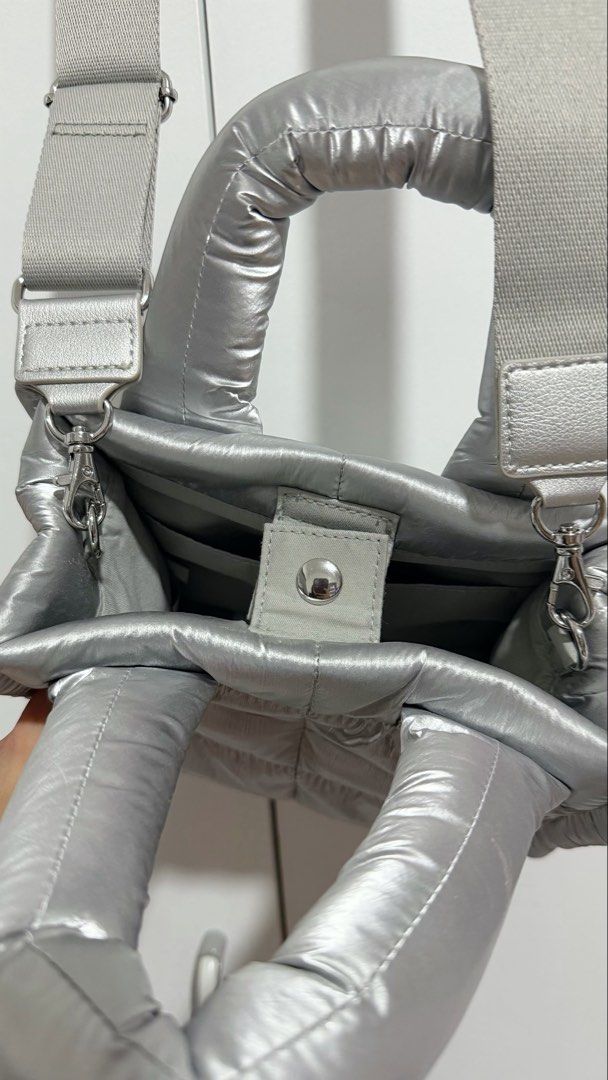 Metallic Silver Puffer Crossbody Bag with Strap (Category: Cross-body Bags) located in Manila. Submitted by trixiasanj76620 (Listing ID 1469792751, Image 2). Description: - Trendy silver metallic puffer tote bag with all-over quilted design - Lightweight and catches the light nicely - Dual puffed top handles and a thick adjustable light grey crossbody strap - Main compartment with a secure center snap button tab - Built-in inside slip pockets for
