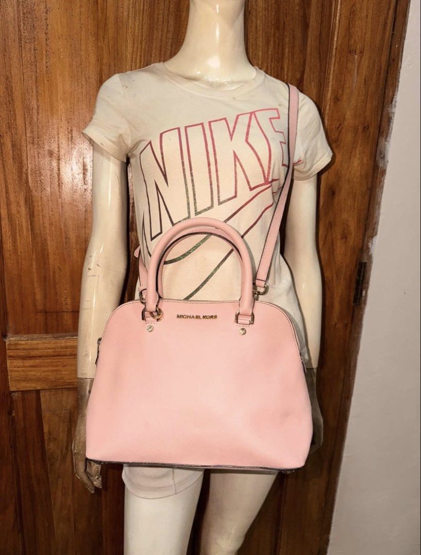 Michael Kors dome/satchel-style (Category: Luxury Bags & Wallets) located in Mati. Submitted by thriftedbagsbeyond (Listing ID 1469920494, Image 2). Description: This is a Michael Kors dome/satchel-style handbag in pink (powder blush / soft pink), most consistent with the Cindy or similar dome satchel models. Key features from the photos • Shape: Classic dome/satchel silhouette with a rounded top. • Exterior: Smooth or lightly textured pink leath