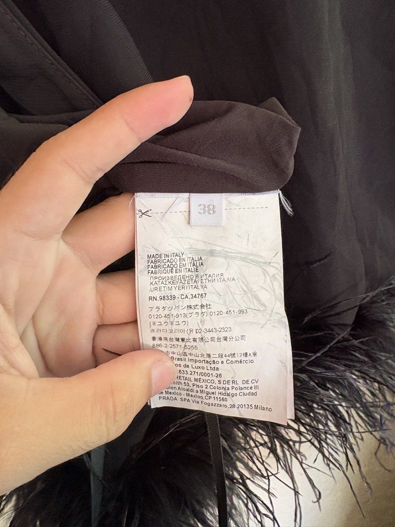 Miu Miu Stretch Cady Halter Top with Feather Hem (Category: Sleeveless) located in Pozorrubio. Submitted by zionegotthrift (Listing ID 1469772046, Image 2). Description: - Brand: Miu Miu - Color: Black - Size: IT 38 - Material: Stretch cady fabric - Details: Eye-catching feather trim on the bottom hem, adjustable back tie closure - Origin: Made in Italy - Condition: Excellent, clean overall - Perfect for: Parties, date nights, and special occasio