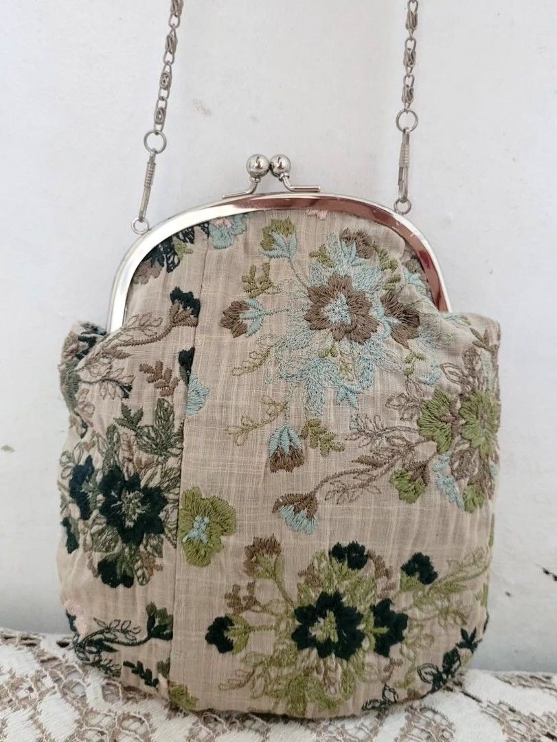 Muted Embroidered Kisslock Bag (Category: Purses & Pouches) located in Balanga. Submitted by marae_c (Listing ID 1469793679, Image 2). Description: In very good condition. Very minimal sign of use. Ery cutesy lang and simple. Embroidered cotton fabric. With kisslock closure and detachable sling chain strap. Measurement. Height: 7" Length: 6.4".