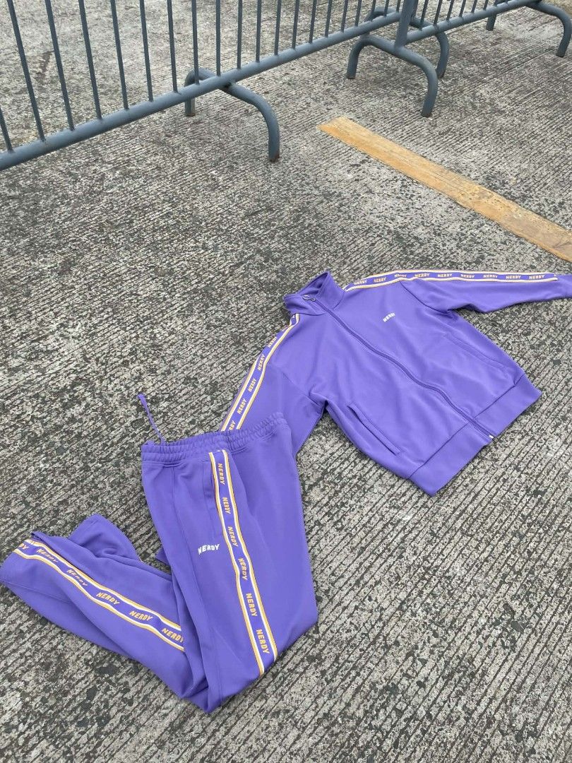 Nerdy Purple Tracksuit Set (Category: Coats, Jackets and Outerwear) located in Manila. Submitted by rarebird-6b79 (Listing ID 1469926606, Image 1). Description: - Purple Nerdy tracksuit set - Features contrasting yellow stripe tape down sleeves and pants with bold branding - Zip-up jacket with stand collar and pockets - Matching pants with elastic drawstring waist and side pockets - Vibrant colorway and super comfy fit.