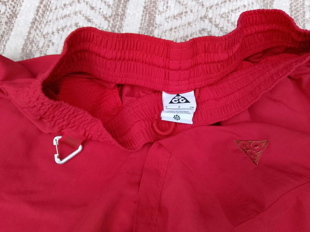 Nike ACG Red Short (Category: Shorts) located in Quezon City. Submitted by cruz_robert (Listing ID 1469808002, Image 2). Description: - Brand: Nike ACG - Color: Bright Red - Size: Small to medium - Condition: Brand new / Excellent - Elastic waistband with interior drawstring for an adjustable fit - Built-in carabiner clip on the front loop for gear attachment - Secure zipper pockets on the sides - Embroidered triangle ACG logo on the lower right 