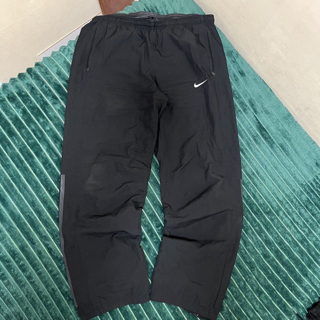 Nike Black Track Pants (Category: Joggers) located in Manila. Submitted by thriftkolngeh (Listing ID 1469935003, Image 1). Description: - Brand: Nike - Item: Windbreaker track pants - Color: Black - Size: XL - Condition: Excellent / Pre-loved (as described) - Waistband: Elastic with adjustable drawcord - Branding: Embroidered white Nike swoosh on left thigh with small logo graphic - Pockets: Secure zip pockets on both sides - Interior: Breathable
