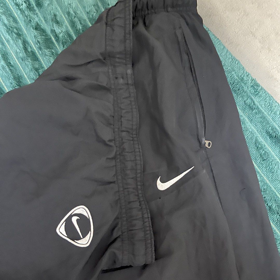 Nike Black Track Pants (Category: Joggers) located in Manila. Submitted by thriftkolngeh (Listing ID 1469935003, Image 2). Description: - Brand: Nike - Item: Windbreaker track pants - Color: Black - Size: XL - Condition: Excellent / Pre-loved (as described) - Waistband: Elastic with adjustable drawcord - Branding: Embroidered white Nike swoosh on left thigh with small logo graphic - Pockets: Secure zip pockets on both sides - Interior: Breathable