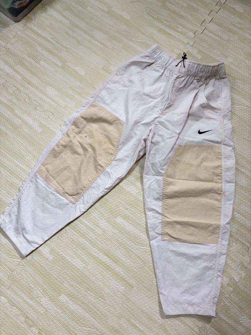 Nike Contrast Patch Nylon Pants Size M (Category: Joggers) located in Quezon City. Submitted by marifavo (Listing ID 1469822362, Image 1). Description: - Brand: Nike - Style: Light pink nylon pants with cream knee patches - Fit/Size: Size Medium with elastic waistband and black drawstring toggle - Flaws: Small brown spot stain on the right knee patch - Condition: Pre-loved, great everyday wear.