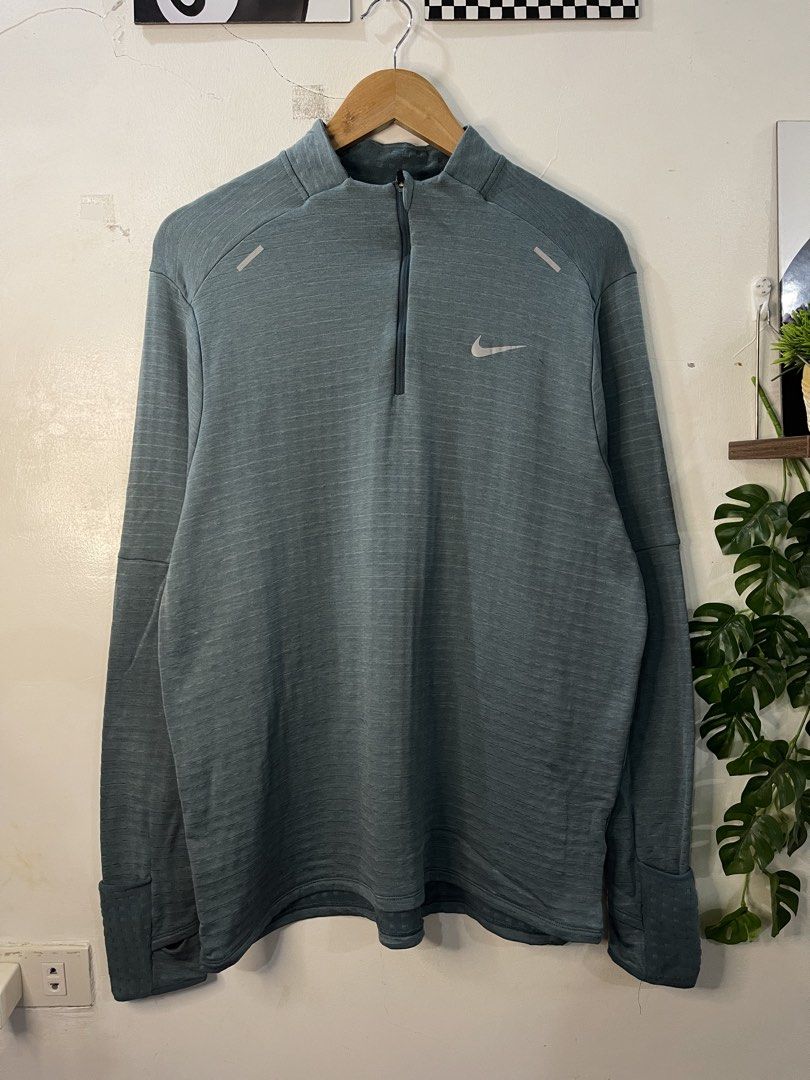 Nike Running Half-Zip Pullover (Category: Coats, Jackets and Outerwear) located in Cabagan. Submitted by blessingma81004 (Listing ID 1469769166, Image 2). Description: - Brand/Model: Nike Running Half-Zip Pullover - Color: Greyish-green - Size: XL (Chest: 22.5", Length: 28") - Material: Smooth exterior with textured waffle-knit interior - Features: Stand-up collar, zip closure, cuff thumbholes, and reflective chest details - Condition: 9.5/10 - N