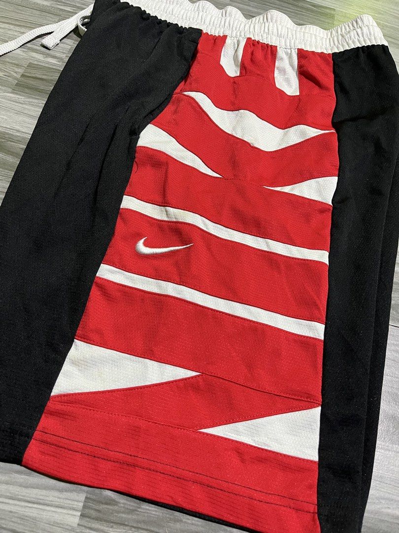Nike Spell out (Category: Shorts) located in Cavite. Submitted by arespichri90266 (Listing ID 1469785051, Image 2). Description: - Brand: Nike - Style: Dri-FIT Basketball Shorts (Style Code: CV1866-010) - Size: Large - Colorway: Black, red, and white with a distinctive striped front panel - Features: Adjustable drawstring waist, white waistband, and embroidered white Nike swoosh - Material: 100% polyester - Origin: Made in Thailand - Condition: C