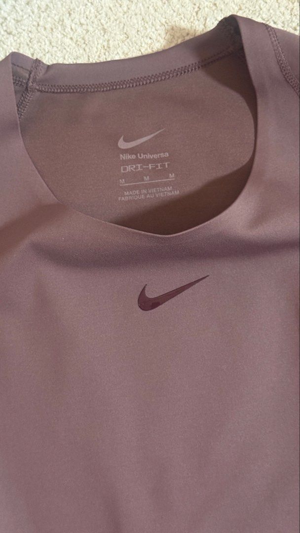 Nike Universa Dri-FIT Short Sleeve Top (Category: Shirts) located in Cabanatuan. Submitted by jstne_ (Listing ID 1469828817, Image 3). Description: - Brand: Nike Universa top - Color: Mauve purple - Size: M (tagged at inner collar) - Material: Dri-FIT (keeps you dry during workouts) - Design: Short sleeves, crew neck, subtle chest swoosh logo - Origin: Made in Vietnam - Condition: Clean, no stains or damage visible.