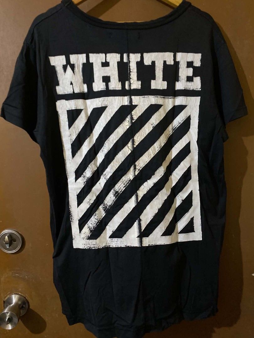 Off-White Black T-Shirt Size L (Category: Shirts) located in Taguig. Submitted by cabugchear34421 (Listing ID 1469879056, Image 2). Description: - Off-White c/o Virgil Abloh - Black - Large (Made in Portugal) - 100% cotton - Iconic diagonal stripes on the back with 'WHITE' text and small horizontal stripes near the front hem ISSUE: Crack prints Bacon neckline (slight).