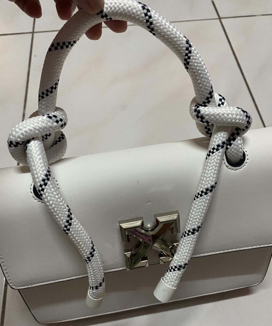 Off-White White Leather Burrow Bag with Rope Handle (Category: Shoulder Bags) located in Manila. Submitted by gutierrez23265 (Listing ID 1469784481, Image 3). Description: Off-White leather handbag in clean white. Distinctive rope top handle with knotted details. Silver tone arrow closure on the front flap. Structured rectangular silhouette with clean black edge painting. Interior slip pocket with subtle debossed logo branding. Removable thin lea