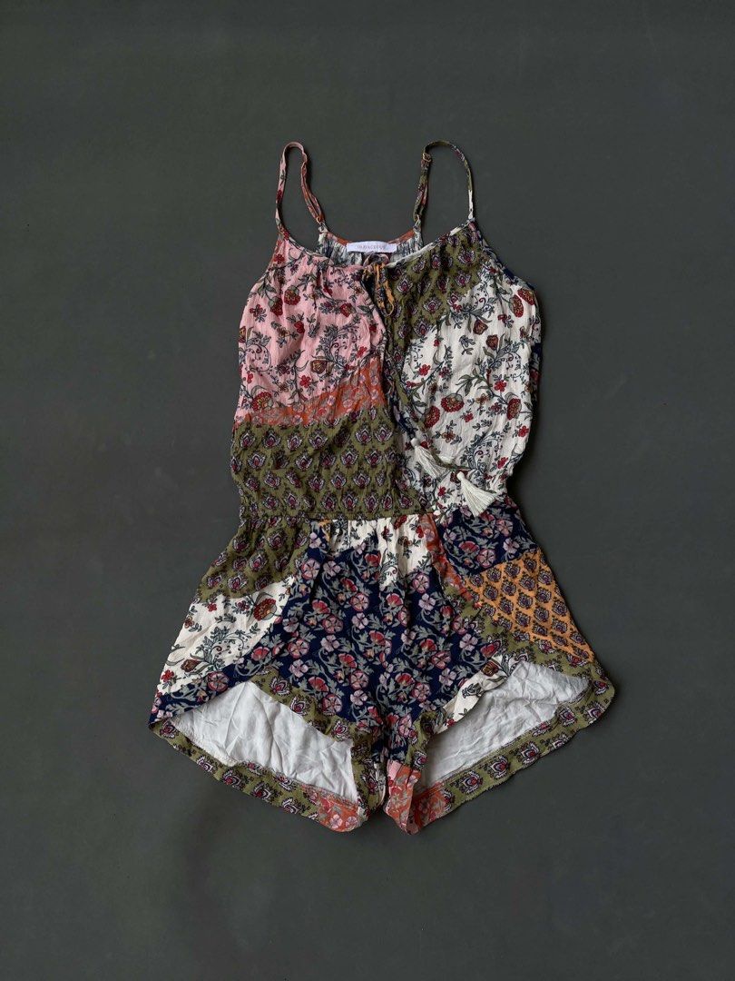 Olivaceous Floral Patchwork Spaghetti Strap Romper Size S (Category: Rompers) located in Baguio. Submitted by lovelaira (Listing ID 1469852811, Image 1). Description: Olivaceous brand, size S. Colorful floral patchwork design with mixed patterns in pink, green, white, and navy blue. Spaghetti straps with adjustable gold-tone sliders. Scoop neckline featuring tassel drawstring ties. Lightweight fabric, cinched elastic waist, flowy shorts construct