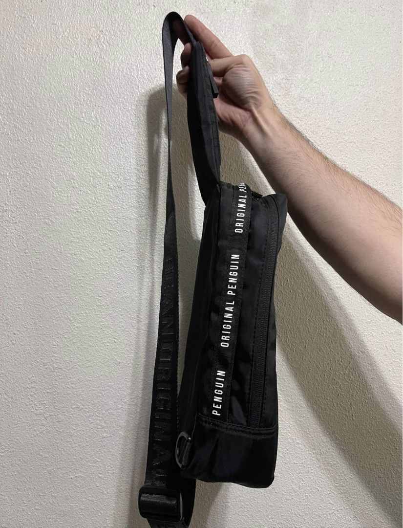 Original Penguin Black Crossbody Sling Bag (Category: Sling Bags) located in Malabon City. Submitted by neon.neon2 (Listing ID 1469908095, Image 2). Description: - Authentic Original Penguin black sling bag - Durable nylon material with branded text straps and zipper pulls - Front vertical white zipper compartment for quick access - Spacious main zip storage compartment - Adjustable strap for shoulder or crossbody wear - Clean condition with mini