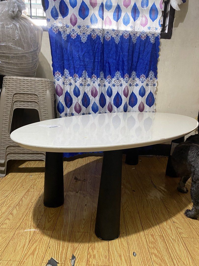 Oval Marble-effect Center Table (Category: Tables & Sets) located in Quezon. Submitted by odd.theprelovedhub (Listing ID 1469800052, Image 1). Description: • Tabletop: White/cream artificial marble or marble-effect finish with an oval shape. • Base: Black cylindrical/sculptural support legs. • Typical Dimensions: Length of 120 cm, width of 60 cm, and standard dining height (around 45 cm) .