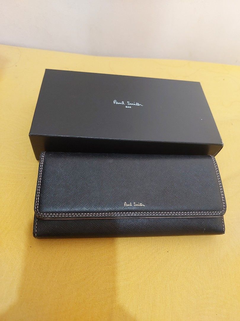 Paul Smith Black Long Wallet with Box PWD526 (Category: Wallets & Card Holders) located in Malabon City. Submitted by jullie_bag_shop (Listing ID 1469816759, Image 3). Description: - Brand: Paul Smith (Model PWD526) - Material: Black textured leather with striking pink interior lining - Design: Elegant flap closure with contrasting stitching - Storage: Multiple card slots, spacious compartments, and a secure zippered coin pocket - Inclusions: Com