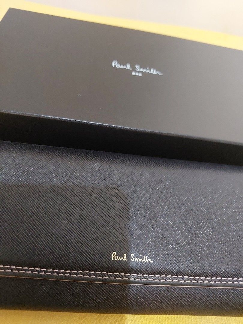Paul Smith Black Long Wallet with Box PWD526 (Category: Wallets & Card Holders) located in Malabon City. Submitted by jullie_bag_shop (Listing ID 1469816759, Image 2). Description: - Brand: Paul Smith (Model PWD526) - Material: Black textured leather with striking pink interior lining - Design: Elegant flap closure with contrasting stitching - Storage: Multiple card slots, spacious compartments, and a secure zippered coin pocket - Inclusions: Com