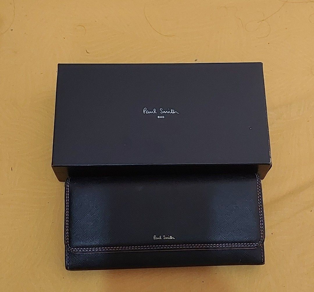 Paul Smith Black Long Wallet with Box PWD526 (Category: Wallets & Card Holders) located in Malabon City. Submitted by jullie_bag_shop (Listing ID 1469816759, Image 1). Description: - Brand: Paul Smith (Model PWD526) - Material: Black textured leather with striking pink interior lining - Design: Elegant flap closure with contrasting stitching - Storage: Multiple card slots, spacious compartments, and a secure zippered coin pocket - Inclusions: Com