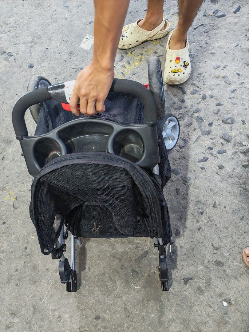 Pet stroller japan surplus (Category: Homes & Other Pet Accessories) located in Manila. Submitted by aks_japansurplus30 (Listing ID 1469809751, Image 2). Description: Black pet stroller for small dogs or cats. Mesh windows provide ventilation and visibility. Includes a top canopy, rear zipper entry, parent tray with cup holders, and a bottom storage basket. Folds down flat for easy transport and storage. Sturdy metal frame with smooth-rolling whe