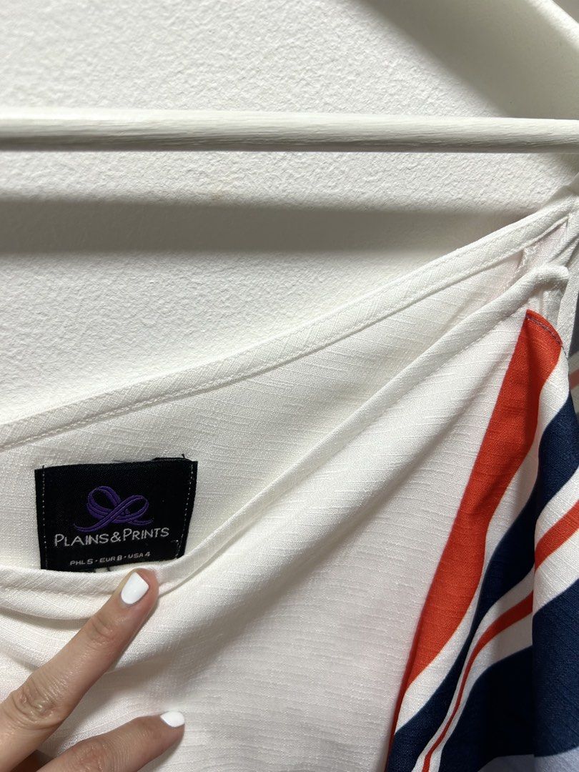 Plains & Prints White Ruffle Camisole Top Size S (Category: Sleeveless) located in Manila. Submitted by isabelle_1104 (Listing ID 1469919439, Image 2). Description: - Brand: Plains & Prints - Style: White sleeveless top with an asymmetrical neckline and thin straps - Detail: Eye-catching red, navy, and light blue striped ruffle panel down the front - Fabric: Lightweight and textured, ideal for warm weather - Size: S on tag (fits EUR 8 / USA 4).