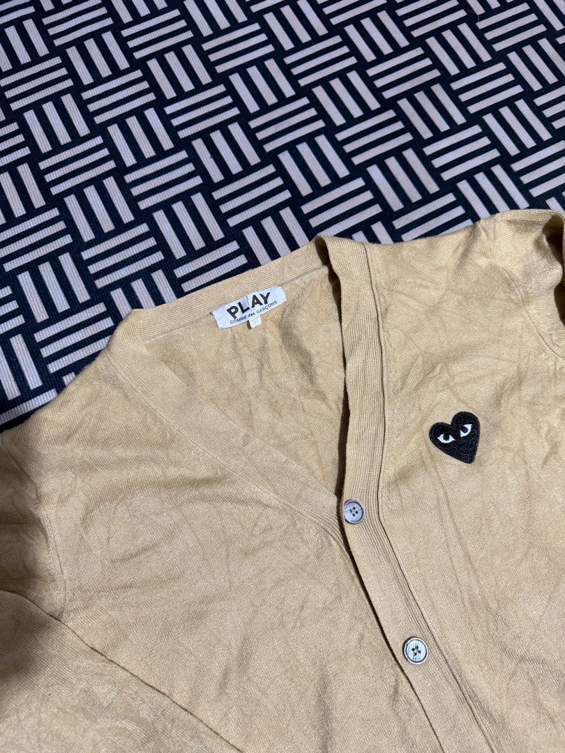 Play Comme des Garçons Beige Cardigan (Category: Coats, Jackets and Outerwear) located in Manila. Submitted by garcianath68674 (Listing ID 1469854043, Image 2). Description: - Brand: Play Comme des Garçons - Color: Beige - Style: V-neck cardigan with front button closure - Detail: Iconic embroidered black heart patch on the left chest - Fit: Ribbed cuffs and hem - Material: Cozy knit fabric, ideal for cooler weather layering - Condition: Excellen