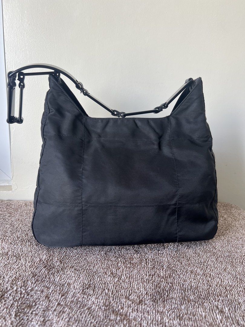 Prada Black Nylon Shoulder Bag (Category: Luxury Bags & Wallets) located in Imus. Submitted by r_mercado (Listing ID 1469894579, Image 2). Description: - Authentic Prada shoulder bag in classic black nylon - Structured plastic and leather link handle strap for a unique look - Silver-tone hardware and iconic enamel triangle logo badge - Interior zip pocket with signature Prada jacquard lining - Clean bottom base with sturdy, durable construction -