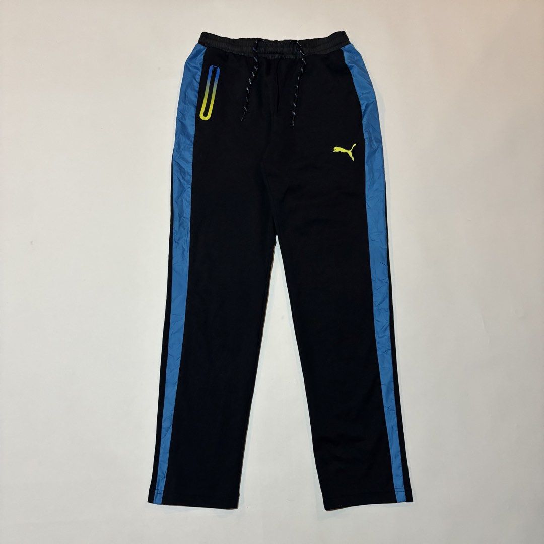 Puma Black Blue Track Pants Size L (Category: Joggers) located in Dipolog. Submitted by dionato (Listing ID 1469865330, Image 2). Description: - Brand: Puma - Color: Black with blue side stripes and neon yellow logo - Size: L (Tag attached) - Material: 100% polyester - Features: Elastic waistband with adjustable drawstring, and one zippered right pocket with a yellow-blue fade detail.