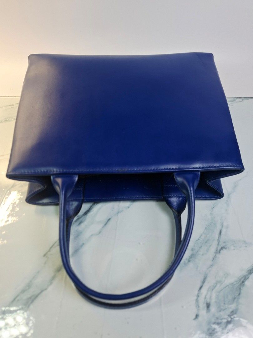 Ra Iride Blue Leather Tote Handbag (Category: Tote Bags) located in Pasay City. Submitted by onick_79 (Listing ID 1469928279, Image 3). Description: - Dimensions: L 30 x H 24 x W 7.5 cm - Brand: Ra Iride - Color: Vibrant blue - Material: Premium leather - Features: Double top handles and exterior zip pocket with branded hardware pull - Protection: Metal feet on the bottom for extra durability - Design: Clean lines, classic shape, and solid struct