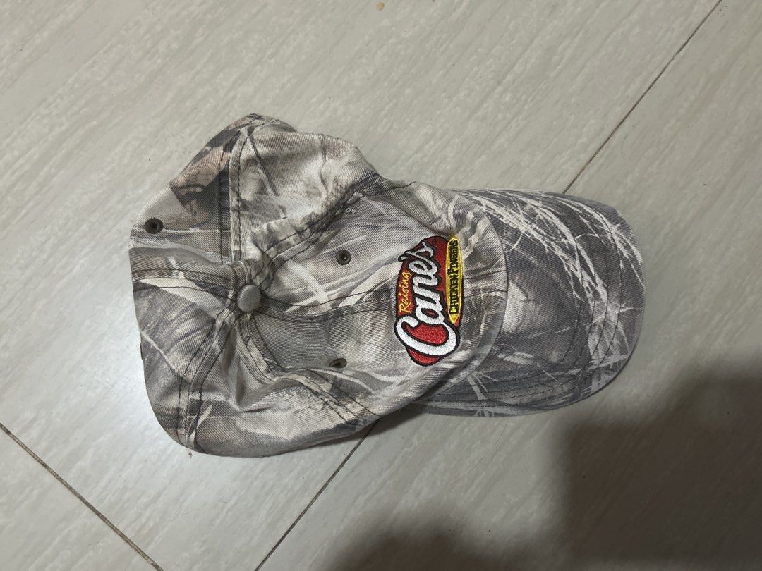 Raising Cane's Camouflage Baseball Cap Hat (Category: Caps & Hats) located in Manila. Submitted by lovely.453 (Listing ID 1469807645, Image 1). Description: - Authentic Raising Cane's restaurant merch - Stylish grey and white camouflage pattern - Embroidered logo patch on the front - Classic unstructured dad hat style - Breathable embroidered eyelets - Clean fabric with crisp stitching.
