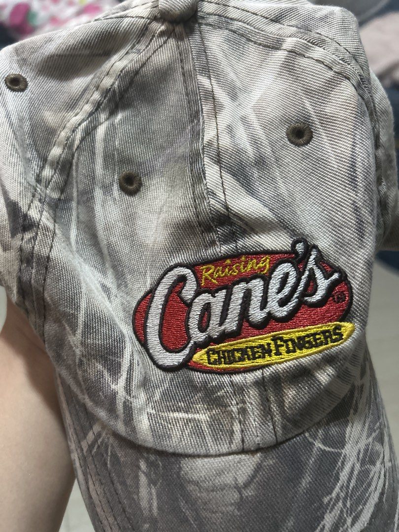 Raising Cane's Camouflage Baseball Cap Hat (Category: Caps & Hats) located in Manila. Submitted by lovely.453 (Listing ID 1469807645, Image 3). Description: - Authentic Raising Cane's restaurant merch - Stylish grey and white camouflage pattern - Embroidered logo patch on the front - Classic unstructured dad hat style - Breathable embroidered eyelets - Clean fabric with crisp stitching.