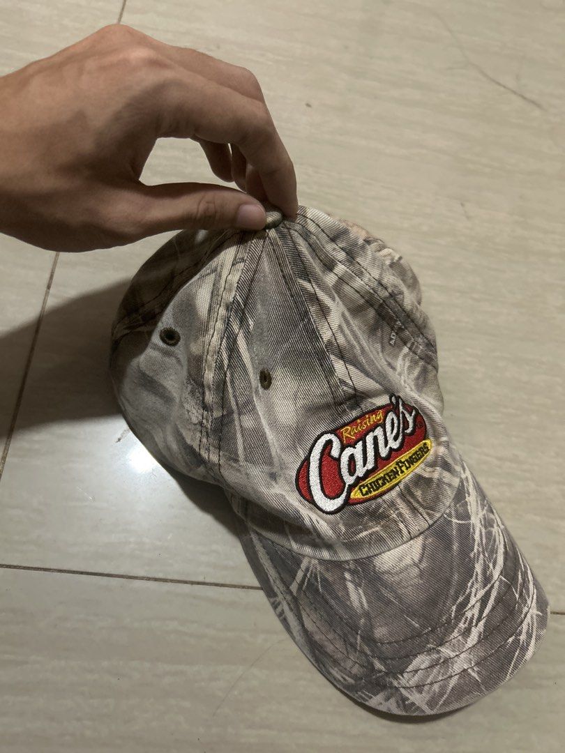Raising Cane's Camouflage Baseball Cap Hat (Category: Caps & Hats) located in Manila. Submitted by lovely.453 (Listing ID 1469807645, Image 2). Description: - Authentic Raising Cane's restaurant merch - Stylish grey and white camouflage pattern - Embroidered logo patch on the front - Classic unstructured dad hat style - Breathable embroidered eyelets - Clean fabric with crisp stitching.