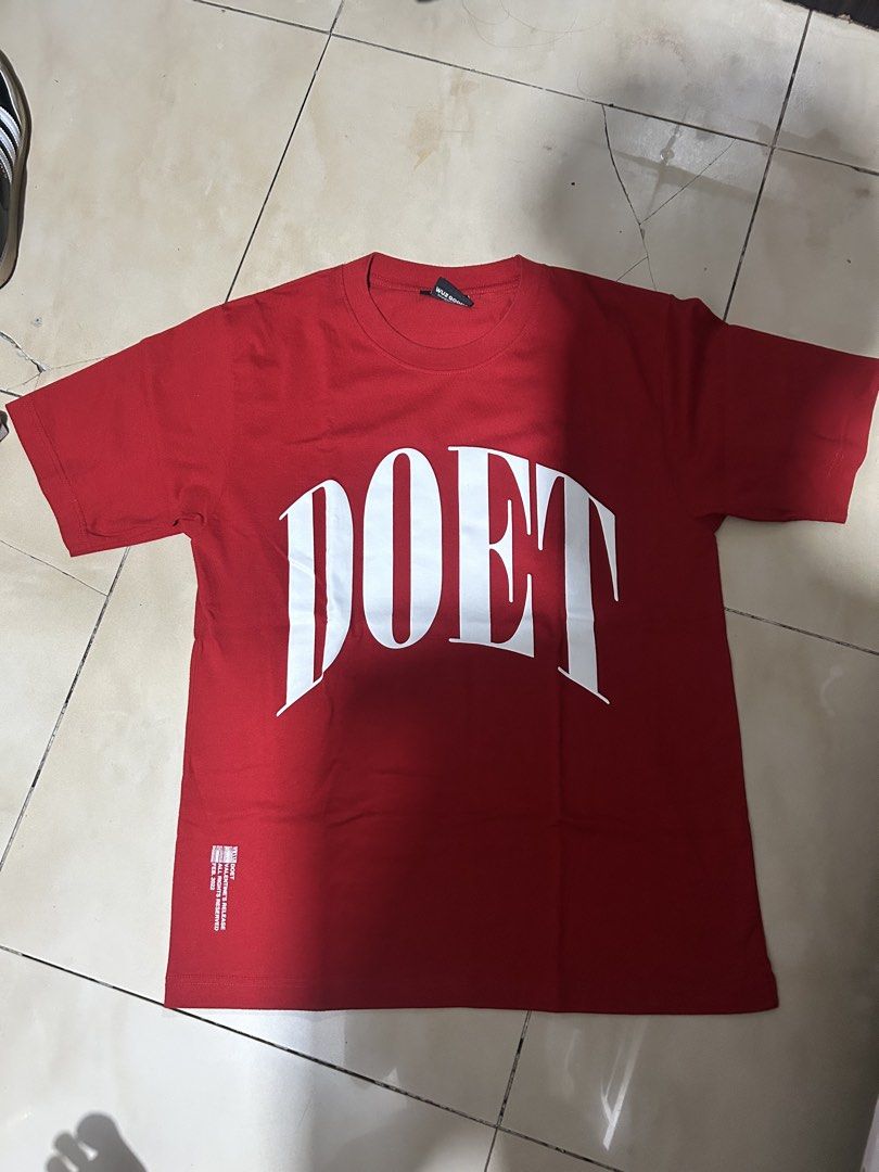 Red DOET Graphic T-Shirt (Category: Tshirts & Polo Shirts ) located in Manila. Submitted by zenforest-7e6908 (Listing ID 1469921668, Image 1). Description: - Color: Bright red - Design: Large white 'DOET' lettering on front with small graphic near bottom hem - Fit: Regular fit with crew neckline and short sleeves - Condition: Clean fabric, no stains or fading - Style: Great casual everyday piece.