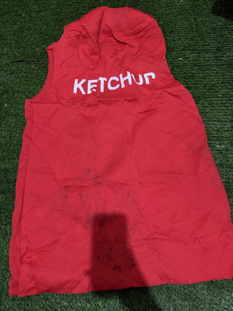 Red Ketchup Costume Tunic (Category: Blouses) located in San Fernando. Submitted by InvisibleMe (Listing ID 1469773330, Image 1). Description: - Bright red ketchup bottle costume top - Sleeveless tunic style with built-in hood and white lettering - Perfect for Halloween, parties, and group costumes - Easy to slip on over any shirt and pants - Condition note: Has wrinkles from storage and some dark stains near the bottom hem.