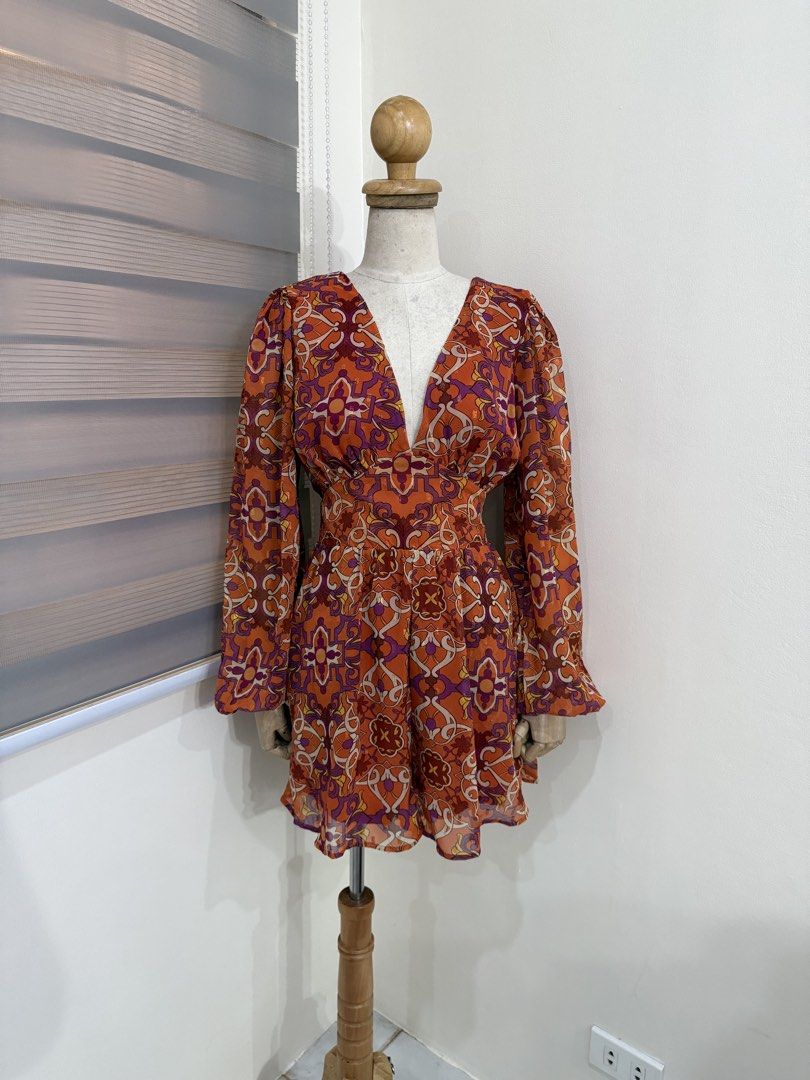 Retro print Long Sleeve Patterned Romper (Category: Dresses) located in Antipolo. Submitted by jackiestash2 (Listing ID 1469862992, Image 2). Description: - Style: Retro vibe, fun statement piece - Color/Pattern: Bright orange with purple and white details - Material: Lightweight chiffon with subtle metallic shimmer, fully lined - Design: Deep V-neckline, long sleeves with ruffled cuffs - Fit: Fitted waist panel with a flared skirt Bust up to 40 