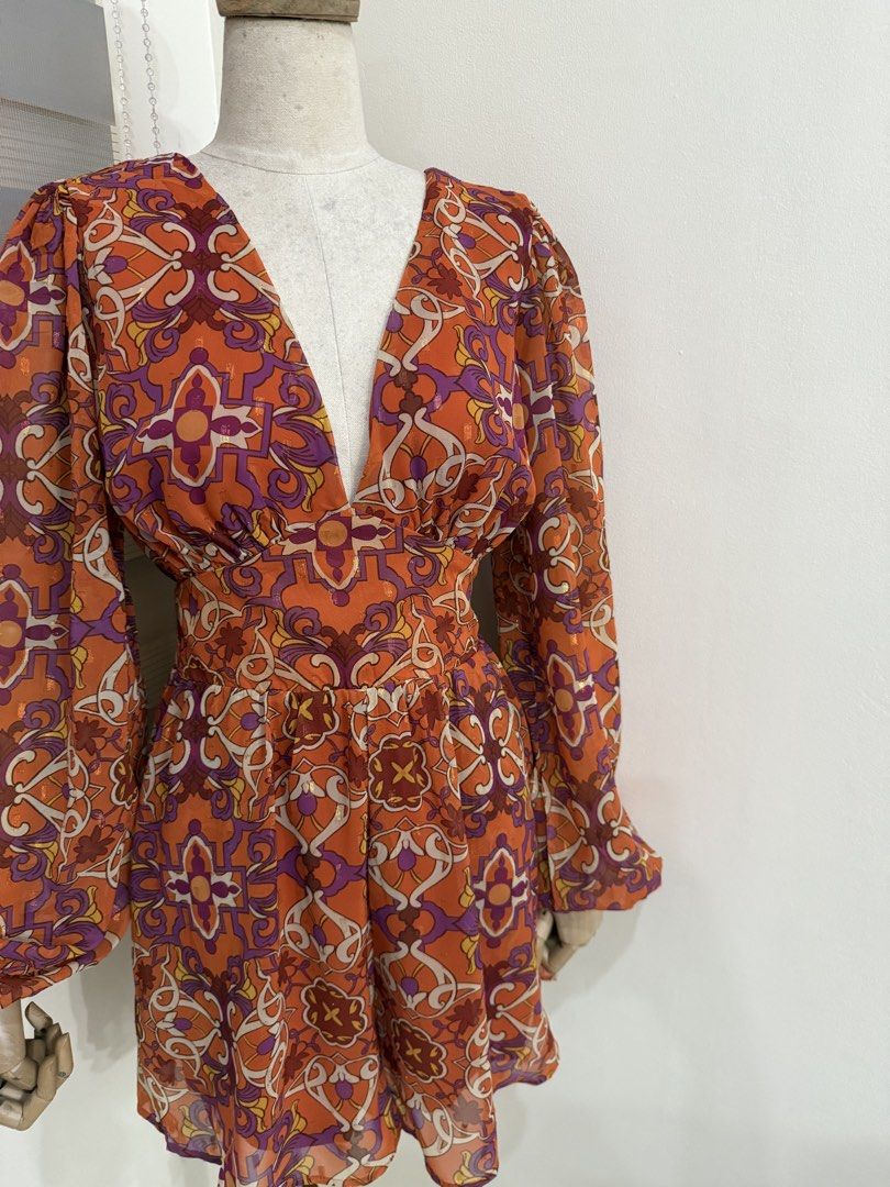 Retro print Long Sleeve Patterned Romper (Category: Dresses) located in Antipolo. Submitted by jackiestash2 (Listing ID 1469862992, Image 3). Description: - Style: Retro vibe, fun statement piece - Color/Pattern: Bright orange with purple and white details - Material: Lightweight chiffon with subtle metallic shimmer, fully lined - Design: Deep V-neckline, long sleeves with ruffled cuffs - Fit: Fitted waist panel with a flared skirt Bust up to 40 
