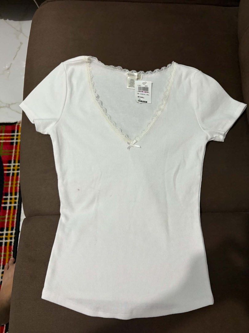 Ribbed V-Neck Top with Lace Trim (Category: Sleeveless) located in Quezon City. Submitted by quickwater_ab40c9 (Listing ID 1469805477, Image 1). Description: - Brand: Hozzzolo - Size: Small (Tag still attached!) - Color: White - Material: Stretchy ribbed cotton - Design: Deep V-neckline with delicate lace trim and center ribbon detail - Condition: Brand new, clean, no stains or damage - Versatility: Great basic piece for layering or wearing on it
