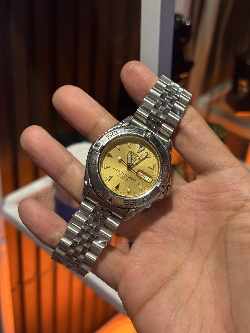 Seiko 5 Automatic Diver Watch Gold Dial (Category: Men's Watches) located in Pasig City. Submitted by gilbert0726 (Listing ID 1469944102, Image 1). Description: Seiko 5 automatic watch with a striking gold dial and rotating bezel. Stainless steel jubilee bracelet still wrapped in protective plastic. Exhibition case back reveals the 23 jewels automatic movement. Water resistant up to 100 meters. Day and date display positioned at the 3 o'clock mar